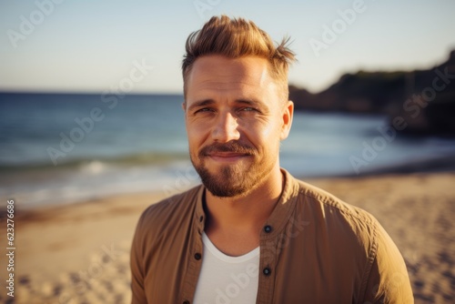 Portrait of a handsome young man standing on the beach and looking at camera