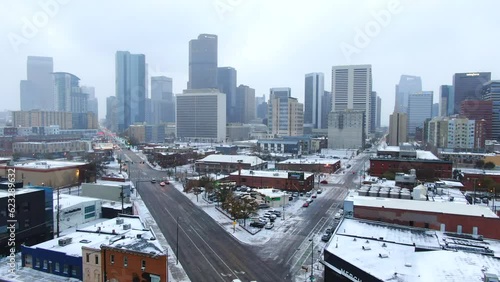 Aerial cinematic drone downtown Denver Colorado city buildings snowing freezing cold winter day gray bird dramatic city landscape car traffic passing cross intersection forward movement photo