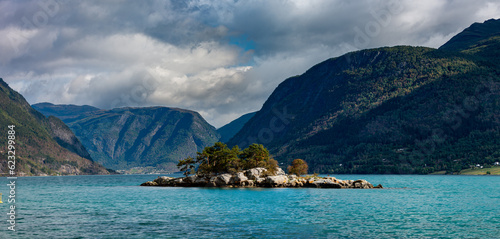 The view from Kåret Beach in Norway towards Lustrafjorden with smal island and its calm waters stretching into the distance