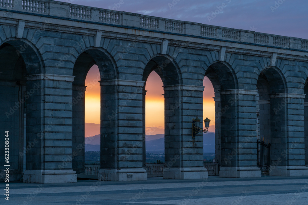 Wall with orange light of sunset shining through three arches at the Royal Palace in Madrid, Spain or the Palacio Real de Madrid. 