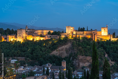 The Alhambra fortress in Granada Spain during the blue hour. Fortress is bathed in golden light, sky is cobalt blue.