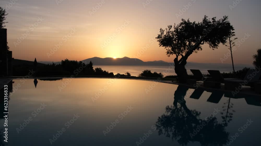 Sunrise behind the mountain. point of view from the pool, next to a tree Sunrise behind the mountain. point of view from the pool, next to a tree