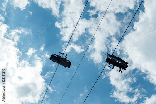 Mountain four-seater chairlift on the background of a blue cloud sky.