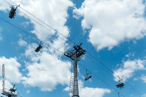 Mountain four-seater chairlift on the background of a blue cloud sky.