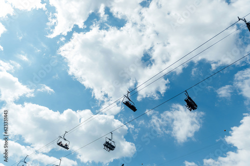 Mountain four-seater chairlift on the background of a blue cloud sky.