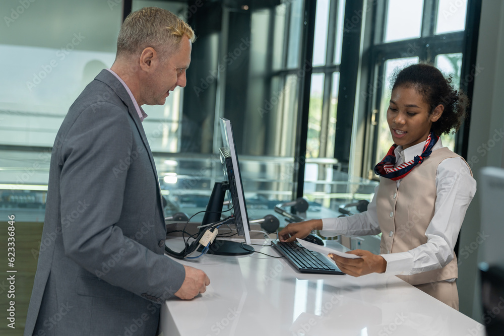Businessman check-in at hotel counter. Female receptionist informs the business man about staying in the hotel. Concept of a reception service counter providing customer information. Businessman check-in at hotel counter. Female receptionist informs the business man about staying in the hotel. Concept of a reception service counter providing customer information.
