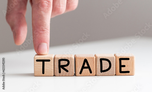 Hand flips cubes and changes the word 'train' to 'trade'. Beautiful wooden table, white background, copy space. Business concept.