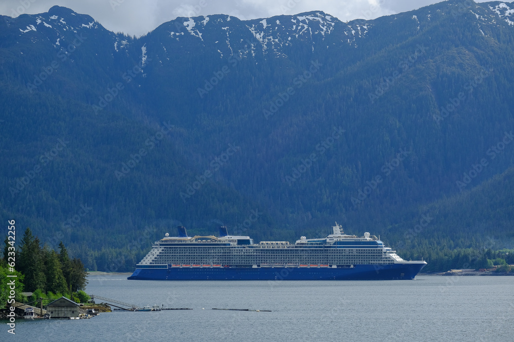 Celebrity cruiseship cruise ship liner Solstice sail away through Sound Bay Fjord Passage from Ketchikan, Alaska towards Inside Passage with mountain range, remote archipelago islands and nature beaut