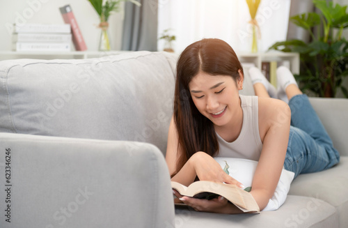 Free Download Asian woman happy smile Beautiful Asian woman relaxing reading book in bedroom at home. home relaxation concept - GFXLoad