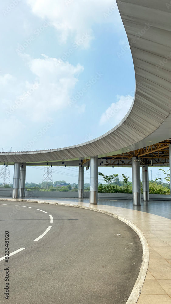 Empty asphalt road in a corner of the bus station. Corner of the Bus station with curving canopy roof against blue sky