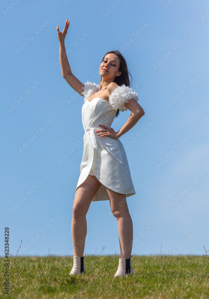 Beautiful brunette woman in a white wedding dress against the blue sky Beautiful brunette woman in a white wedding dress against the blue sky