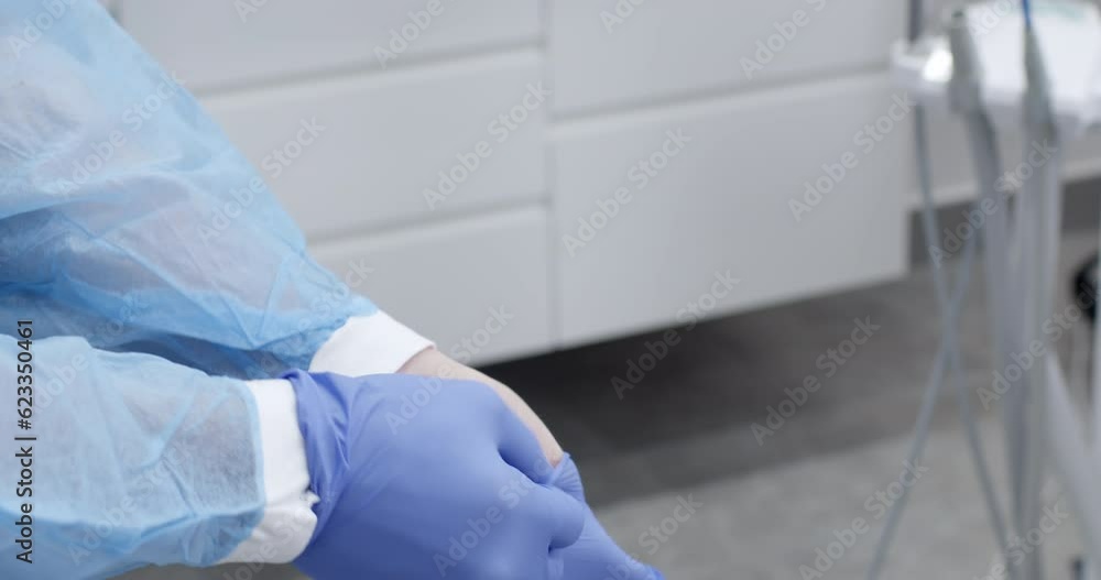 Close-up, the doctor puts on gloves on non-sterile hands in the medical office, preparing for the operation. Close-up, the doctor puts on gloves on non-sterile hands in the medical office, preparing for the operation.