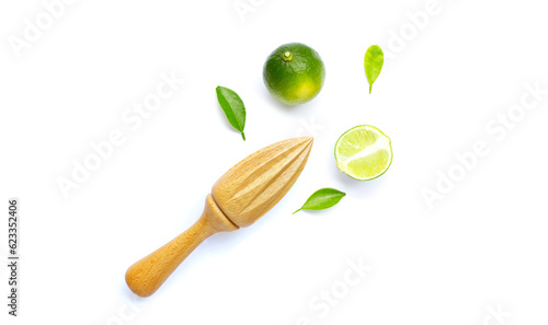 Fresh limes and leaves with wooden juicer on white background.