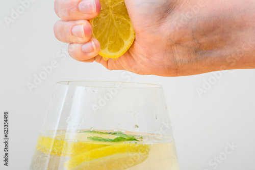 Cytryna wyciskana w dłoniach do szklanki z wodą 