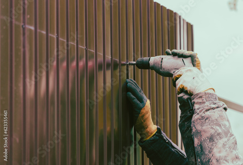 Workers install a metal profile fence