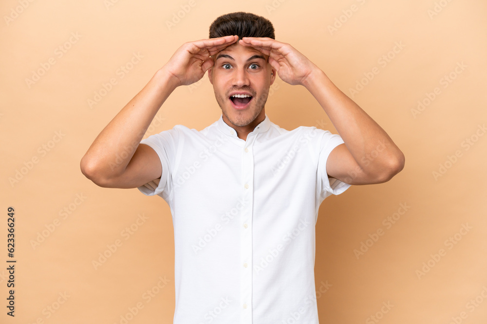 Young caucasian man isolated on beige background with surprise expression Young caucasian man isolated on beige background with surprise expression