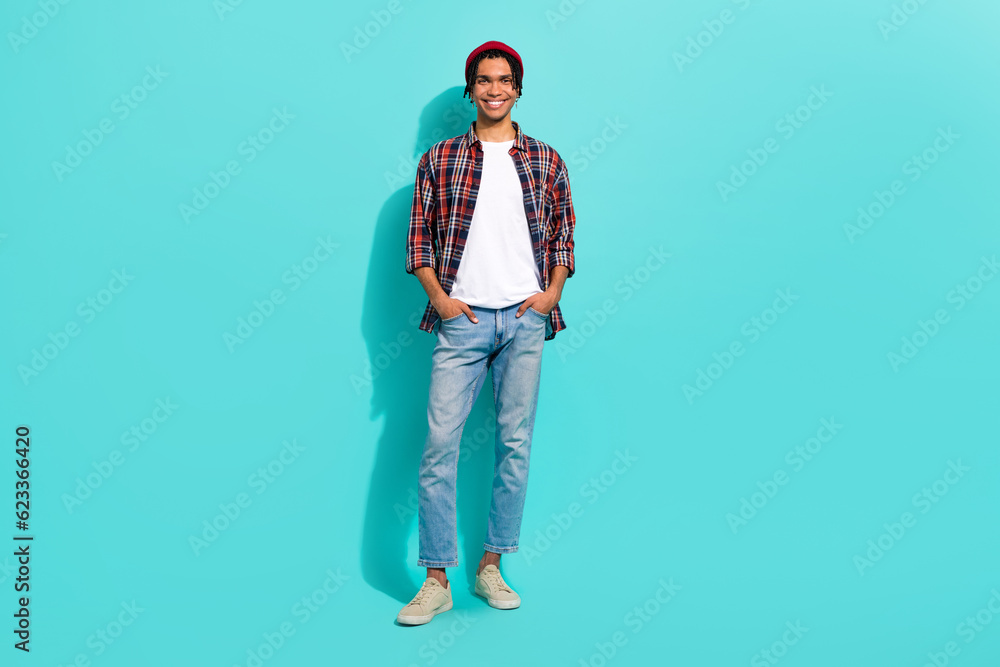 Fototapeta premium Full length photo of positive satisfied young person put hands pockets posing isolated on teal color background