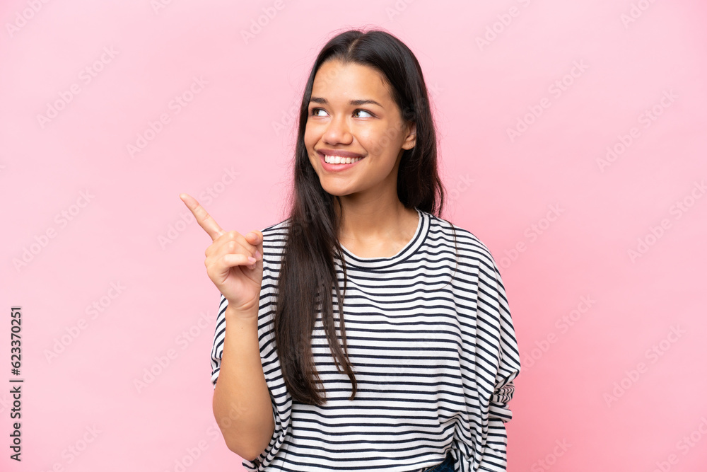 Young Colombian woman isolated on pink background intending to realizes the solution while lifting a finger up Young Colombian woman isolated on pink background intending to realizes the solution while lifting a finger up