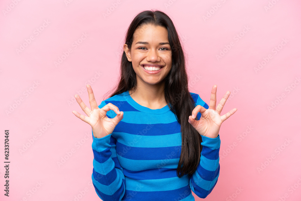 Young Colombian woman isolated on pink background showing ok sign with two hands Young Colombian woman isolated on pink background showing ok sign with two hands