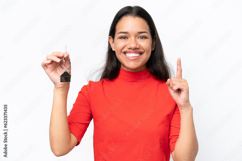 Young Colombian woman holding home keys isolated on white background pointing up a great idea Young Colombian woman holding home keys isolated on white background pointing up a great idea