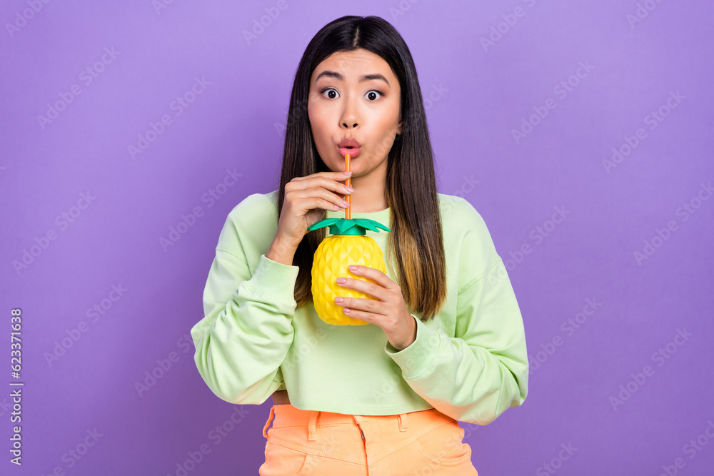 Photo of astonished impressed pretty woman dressed green shirt drink tasty beverage from ananas cup isolated on purple color background Photo of astonished impressed pretty woman dressed green shirt drink tasty beverage from ananas cup isolated on purple color background
