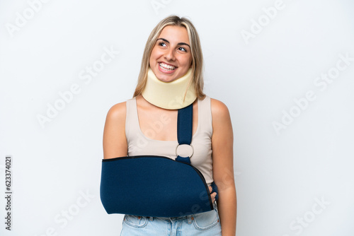 Woman with broken arm and wearing a sling isolated on white background thinking an idea while looking up
