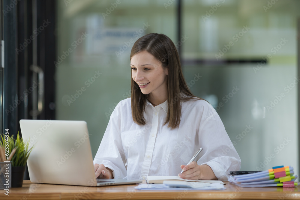 A businesswoman or accountant using writing a notebook while working on an analytic business report on a laptop computer at the workplace, Planning financial and accounting concepts.
A businesswoman or accountant using writing a notebook while working on an analytic business report on a laptop computer at the workplace, Planning financial and accounting concepts.