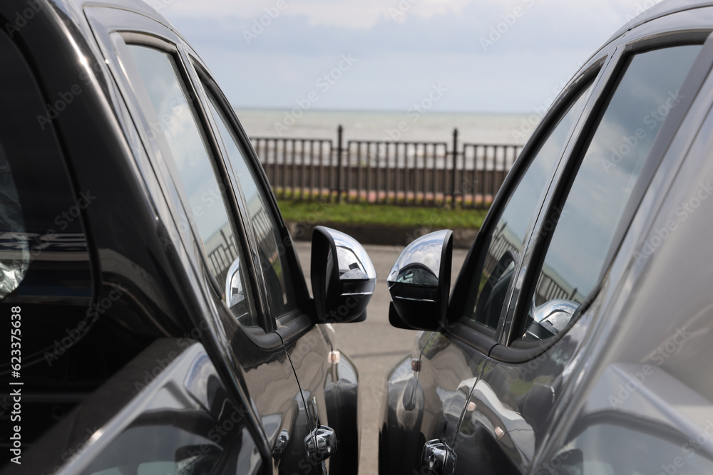 Closeup shot of two new modern pick up cars parked next to each other.  window to window.  folded rear view mirrors.