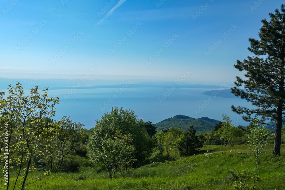 A panoramic view on the Mediterranean Sea in Croatia from Vojak. The mountain is overgrown with lush green plants. Few islands in the back. Early morning hiking by the sea. Clear, blue sky. Remedy A panoramic view on the Mediterranean Sea in Croatia from Vojak. The mountain is overgrown with lush green plants. Few islands in the back. Early morning hiking by the sea. Clear, blue sky. Remedy