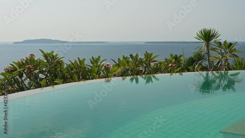Slow calming pan over the infinity pool with views across the Gilli islands in Indonesia photo