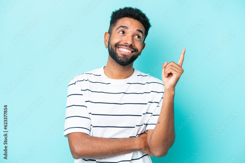 Young Brazilian man isolated on blue background pointing up a great idea Young Brazilian man isolated on blue background pointing up a great idea