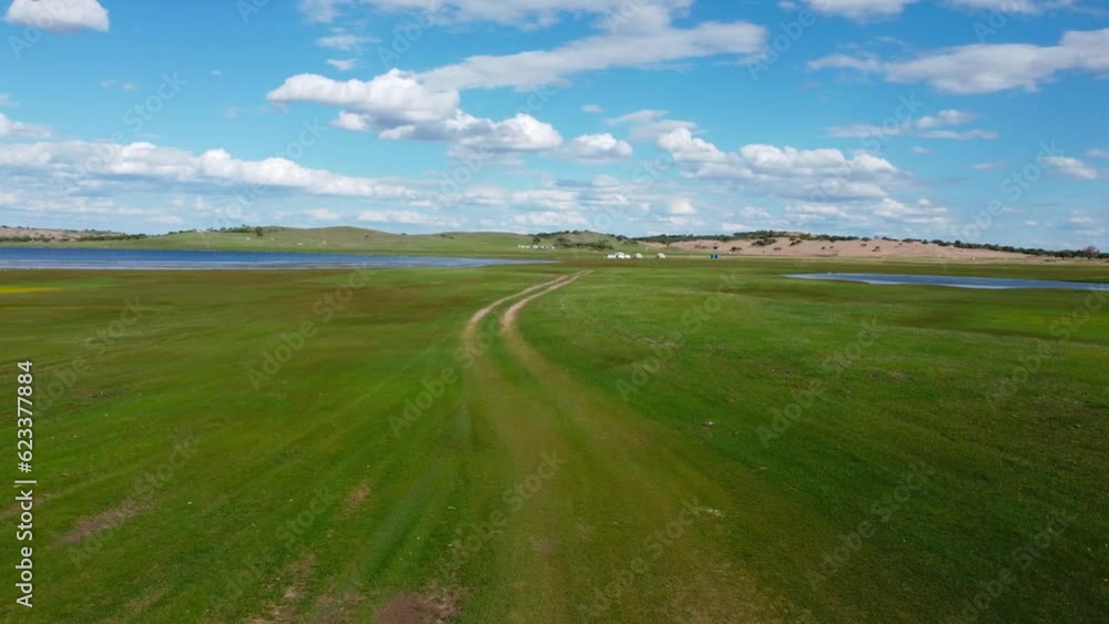 Large green meadow with a lake in the background. Forward aerial shot. Grassland Desert Large green meadow with a lake in the background. Forward aerial shot. Grassland Desert