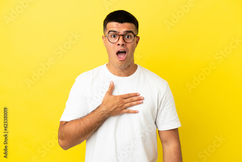 Young handsome man over isolated yellow background surprised and shocked while looking right