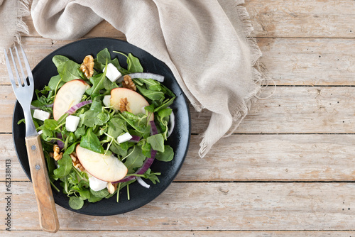 Autumn salad with apples and walnuts on wooden table. Top view. Copy space photo