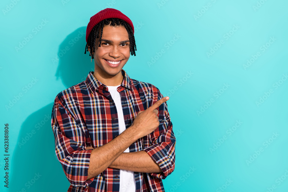 Photo portrait of nice young guy point empty space representative agent dressed stylish checkered clothes isolated on cyan color background