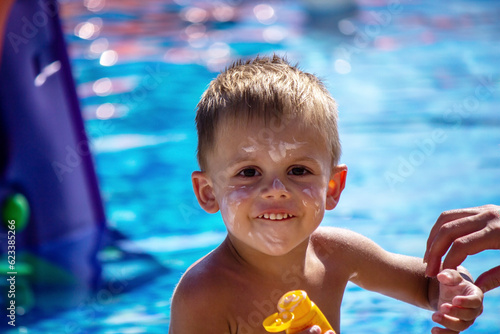 a boy in the pool smeared with suntan cream.