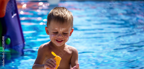 a boy in the pool smeared with suntan cream.