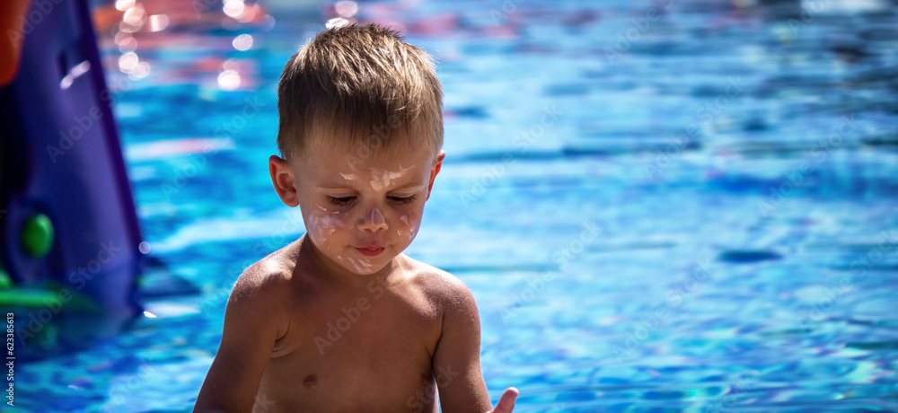 a boy in the pool smeared with suntan cream.