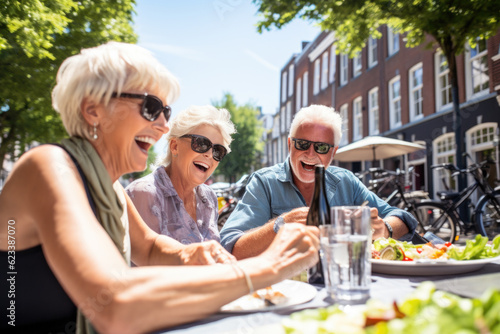 Happy group of senior people drinking, eating and laughing together on vacation in Amsterdam. Pensioners having fun together on summer holiday