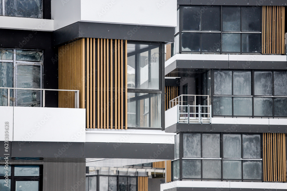 Concept of investment in building industry. Facade or front view of new and modern house with metal window frames and open balcony. Concept of mortgage loan for apartment Concept of investment in building industry. Facade or front view of new and modern house with metal window frames and open balcony. Concept of mortgage loan for apartment