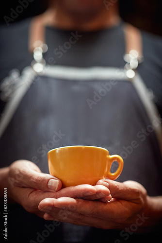 man holding with both hands orange cup of coffee. copy space