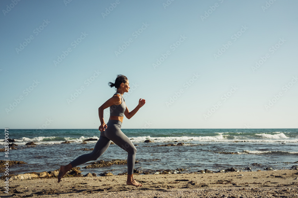 a beautiful brunette girl in gray leggings is engaged in fitness on the sand against the background of the sea a beautiful brunette girl in gray leggings is engaged in fitness on the sand against the background of the sea