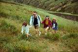 Loving, caring family, man and woman going hiking with their children. Walking on trails, hills, fields Beautiful summer nature landscape. Concept of leisure time, fun, nature, active lifestyle