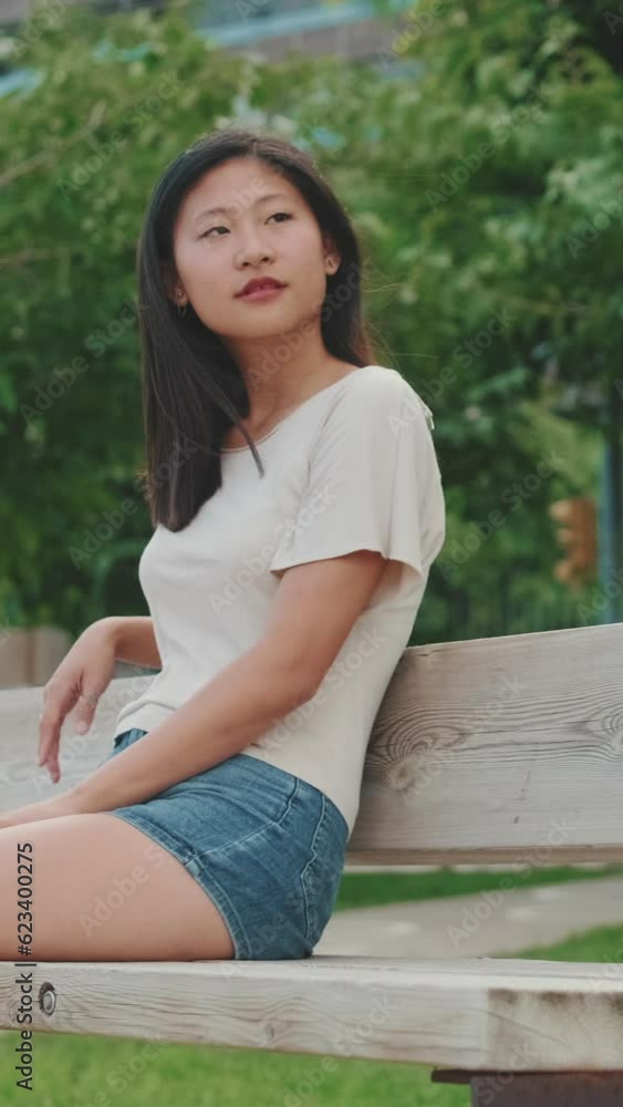 Young woman resting sitting on bench in city park, looking around Young woman resting sitting on bench in city park, looking around