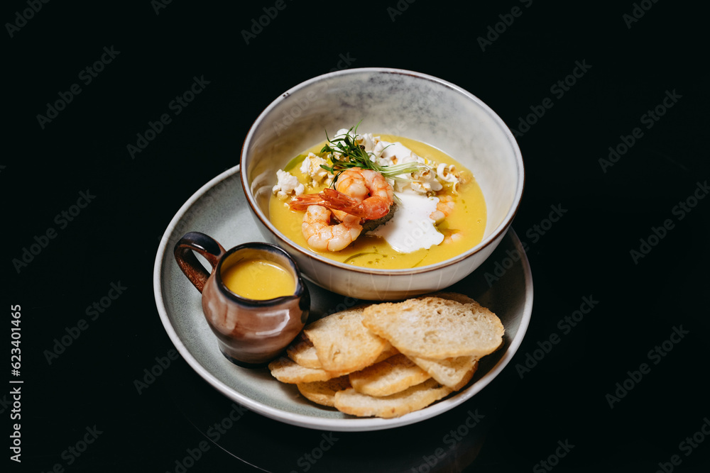 Cream soup with shrimp on a black background