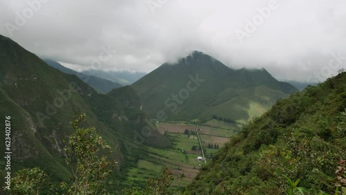 Valley beneath high Ecuador green hills with cloudy sky. High wide static.