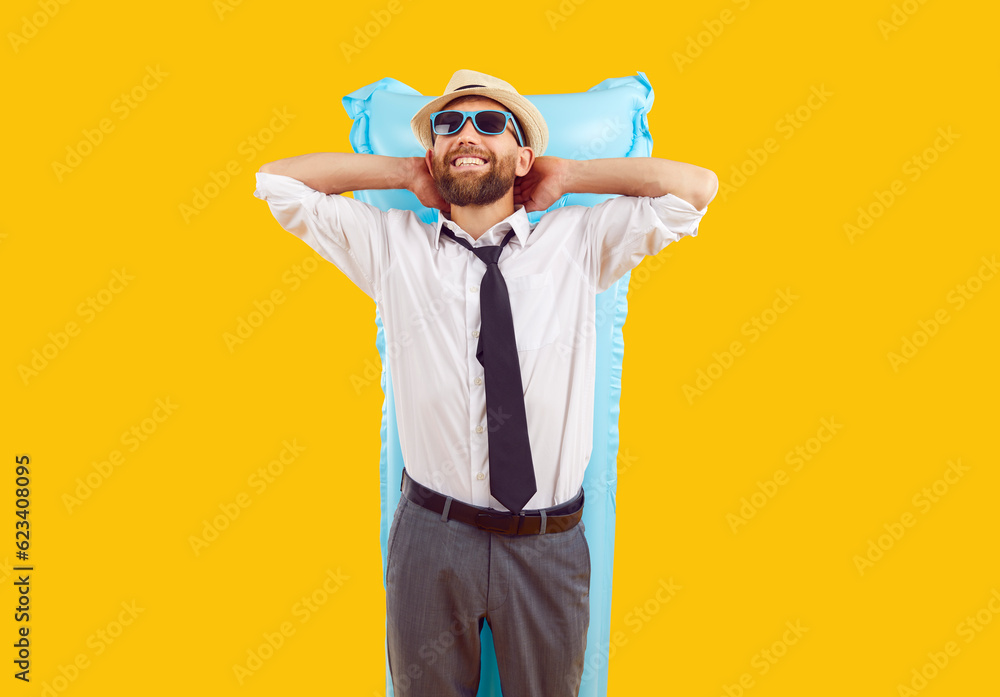 Happy funny man in sunglasses and office clothes with a white shirt and tie lying on inflatable mattress isolated on a studio yellow background. Guy dreaming of swimming on a beach. Vacation concept.