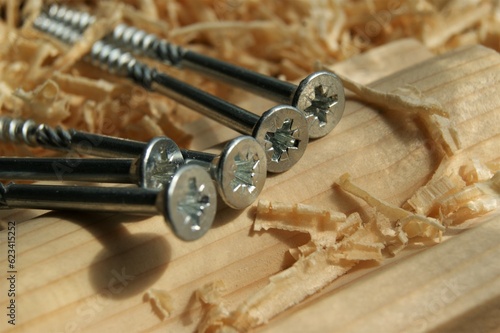 Carpentry, construction. Close-up of metal screws on wooden board.
