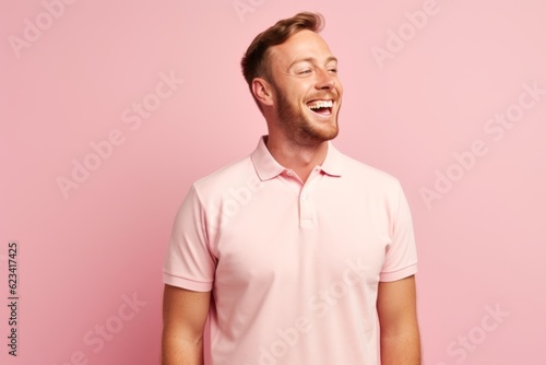 Lifestyle portrait photography of a happy boy in his 30s wearing a sporty polo shirt against a pastel pink background. With generative AI technology