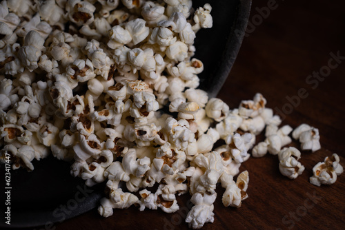 Close up of Puffed light golden popcorns on dark wooden serving tray